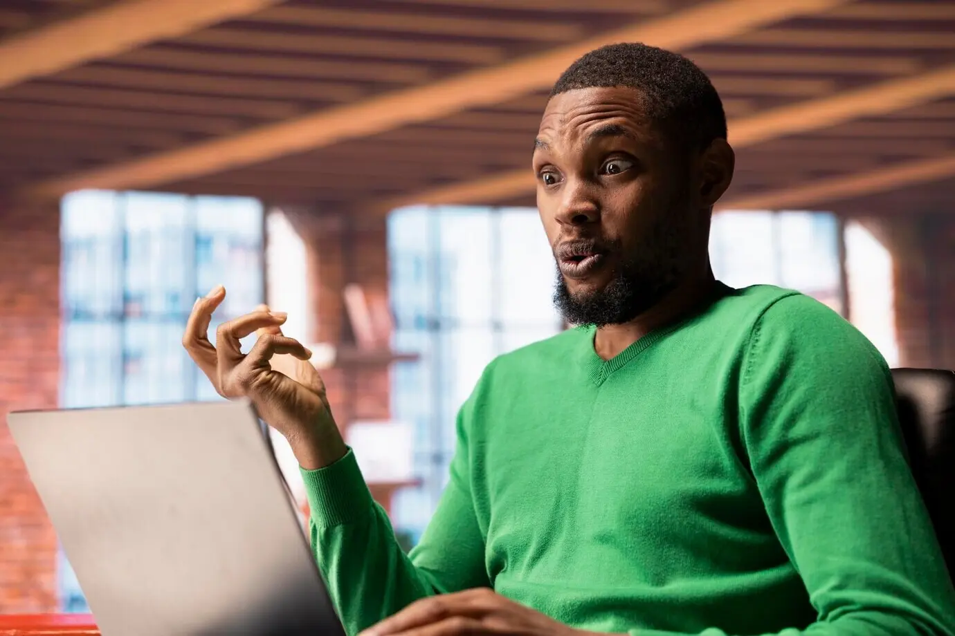 Мужчина дома смотрит телешоу на ноутбуке и шокирован интересным поворотом сюжета.