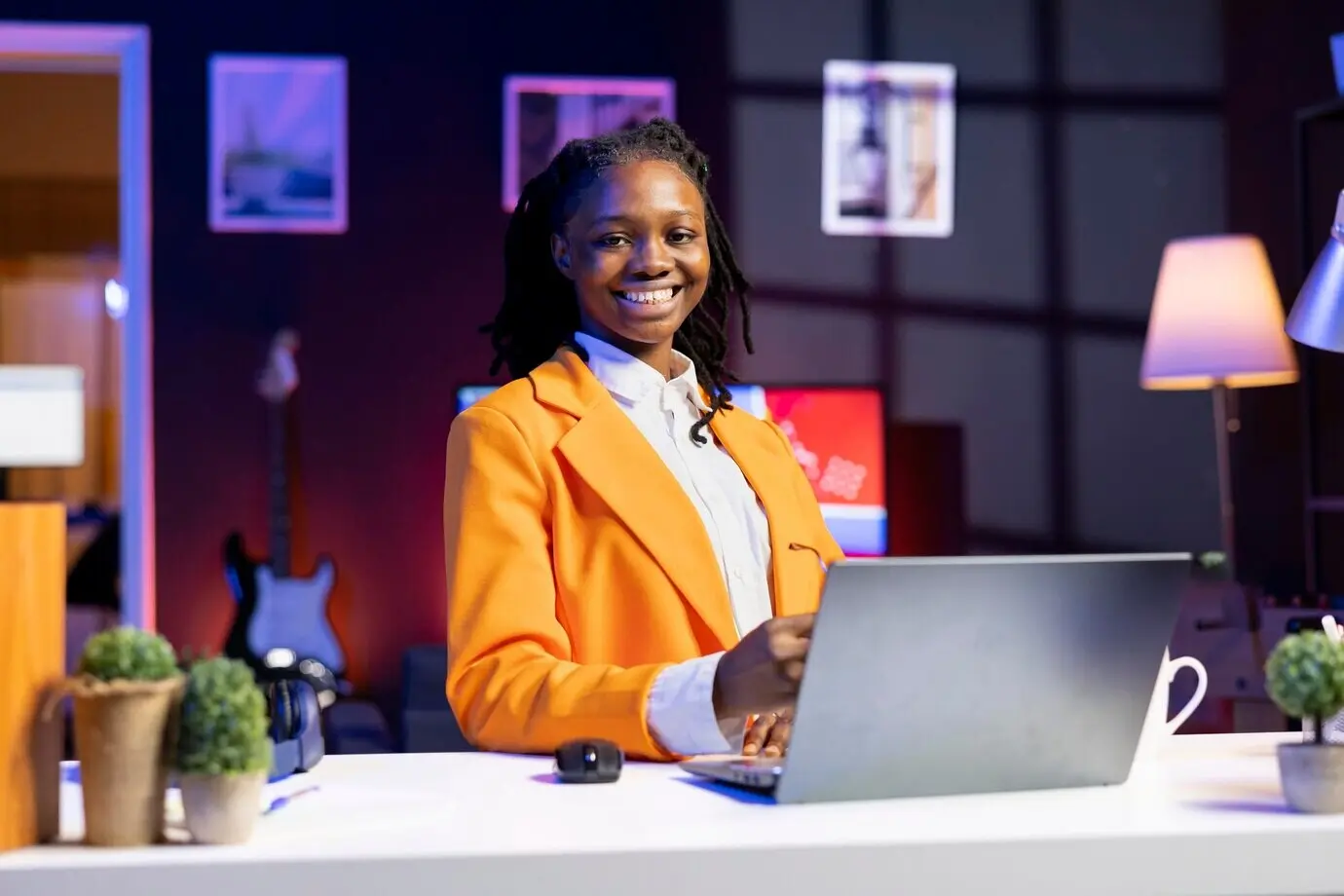 Портрет улыбающегося фрилансера в домашнем офисе, оптимизирующего KPI на ноутбуке.